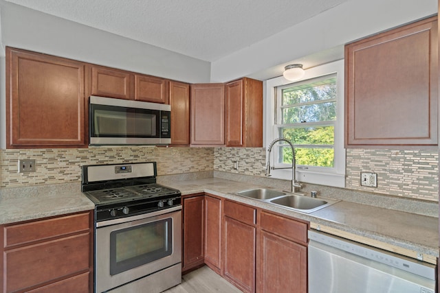 kitchen featuring tasteful backsplash, sink, stainless steel appliances, and a textured ceiling