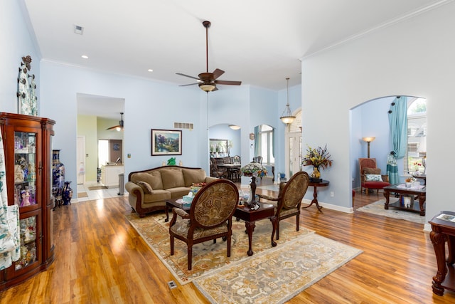 living room featuring a towering ceiling, ornamental molding, and hardwood / wood-style floors