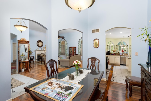 dining space featuring a towering ceiling, ceiling fan, and light wood-type flooring