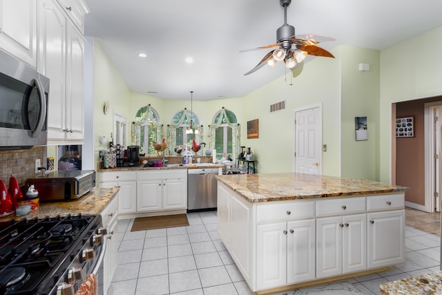 kitchen with white cabinetry, appliances with stainless steel finishes, a kitchen island, and light tile patterned floors