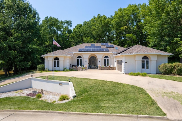 mediterranean / spanish-style home with a garage, a front lawn, and solar panels