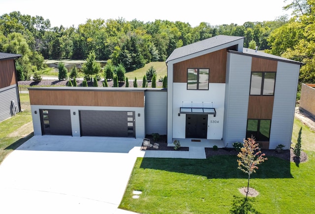 contemporary house featuring a garage, concrete driveway, and a front lawn