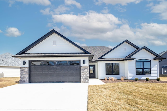 view of front of house with a front lawn, concrete driveway, stone siding, and an attached garage