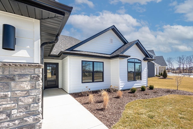 exterior space with a yard and roof with shingles