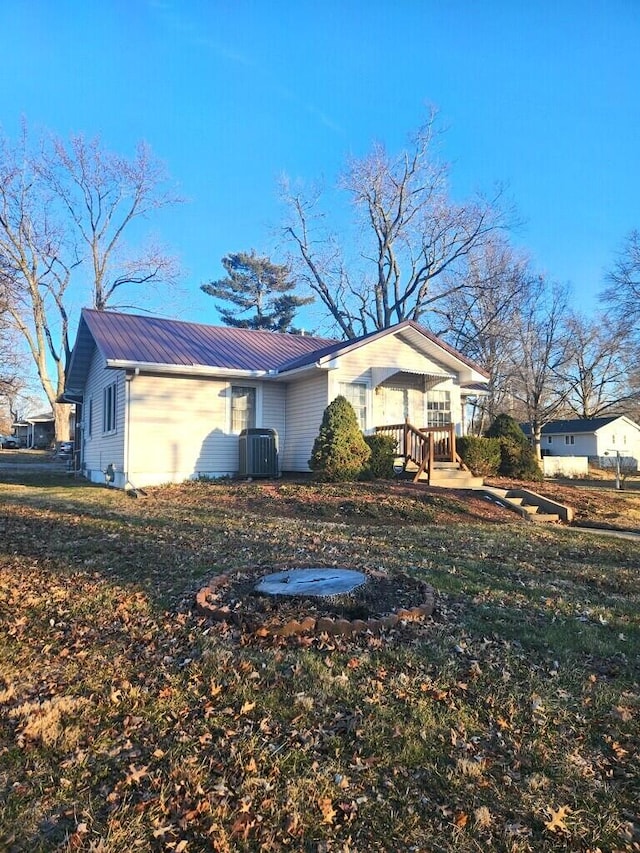 exterior space featuring covered porch, a lawn, and central air condition unit