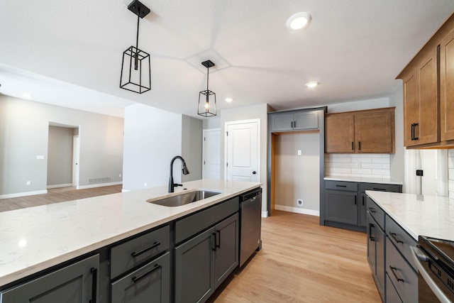 kitchen with appliances with stainless steel finishes, sink, hanging light fixtures, light stone countertops, and tasteful backsplash