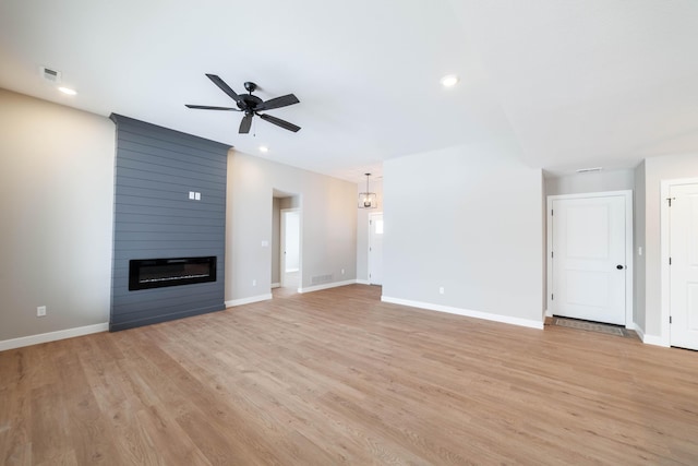 unfurnished living room featuring ceiling fan, a large fireplace, and light hardwood / wood-style floors