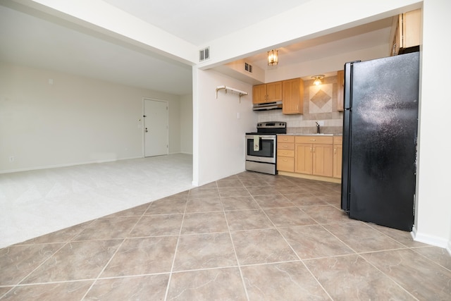 kitchen with decorative backsplash, light brown cabinets, light tile patterned floors, black fridge, and stainless steel electric stove