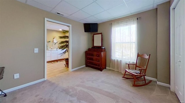 sitting room with a paneled ceiling and carpet