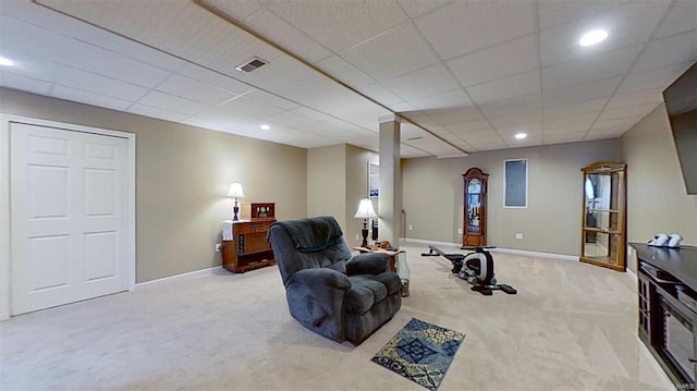 carpeted living room featuring a drop ceiling