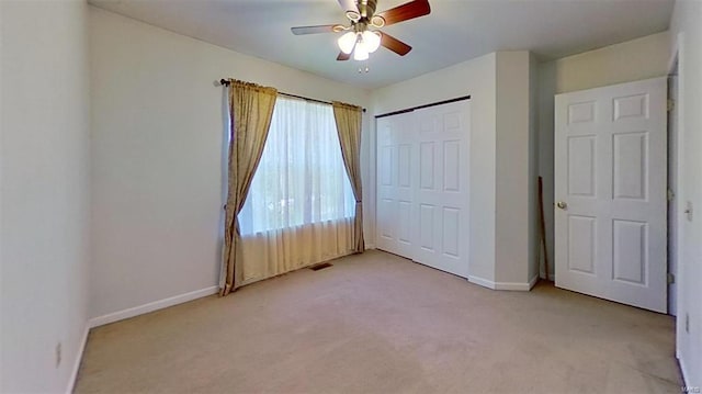 unfurnished bedroom featuring ceiling fan, light carpet, and a closet