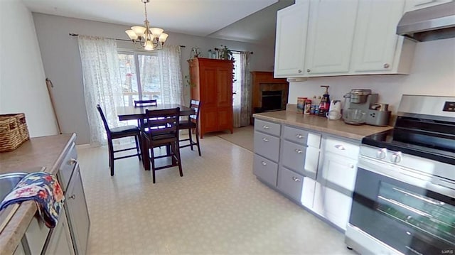 kitchen featuring electric stove, pendant lighting, a chandelier, and white cabinets