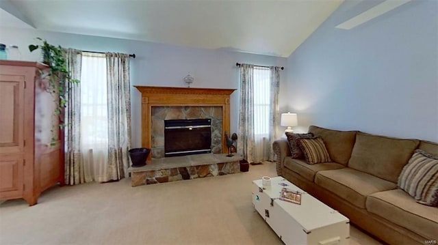 carpeted living room with lofted ceiling and a stone fireplace