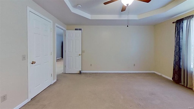 carpeted spare room featuring a raised ceiling and ceiling fan