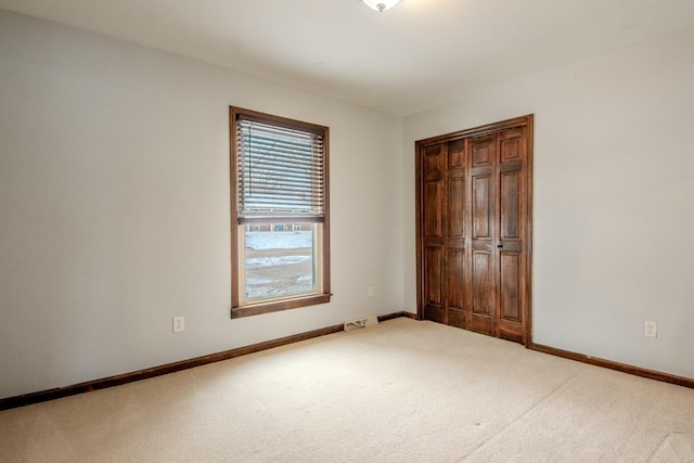 unfurnished bedroom with baseboards, a closet, visible vents, and light colored carpet