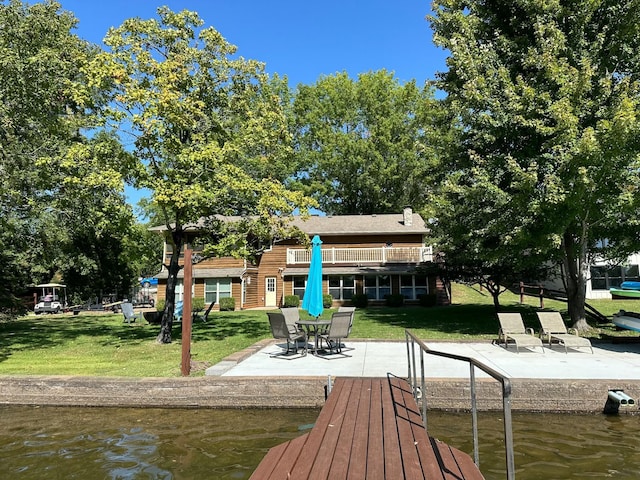 dock area featuring a patio area, a water view, a yard, and a balcony