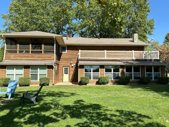 back of house with a sunroom, a lawn, a chimney, and a balcony