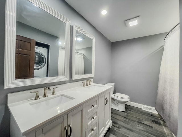 bathroom with wood tiled floor, stacked washer and clothes dryer, a sink, and toilet