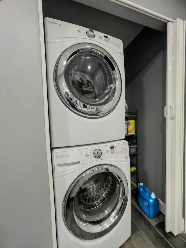 laundry area with stacked washer and dryer, laundry area, baseboards, and wood finished floors