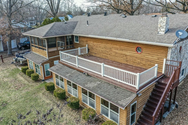 rear view of property with a chimney, a shingled roof, stairway, a sunroom, and a wooden deck