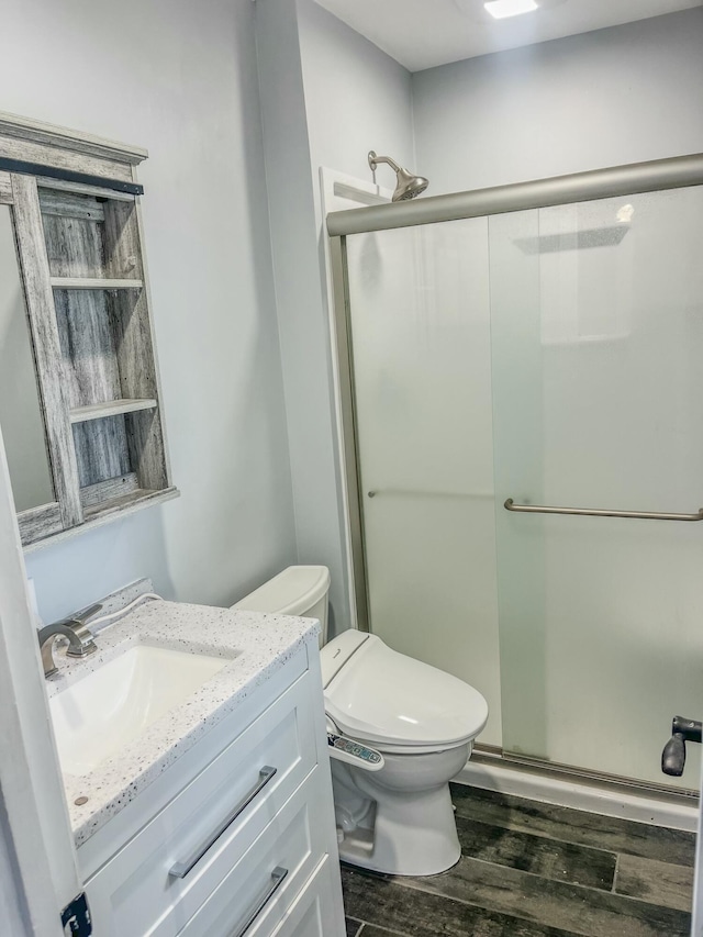 full bath with vanity, a stall shower, wood finished floors, and toilet