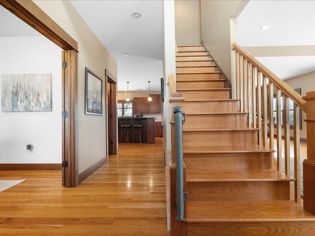 staircase featuring baseboards, wood finished floors, and recessed lighting