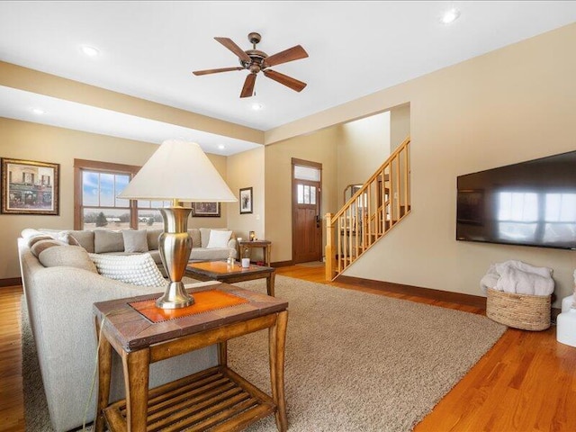 living area with recessed lighting, wood finished floors, baseboards, and stairs