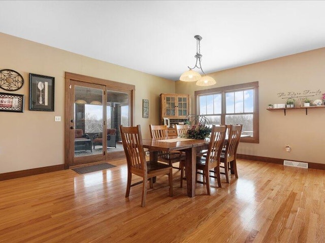 dining room with baseboards, visible vents, and light wood finished floors