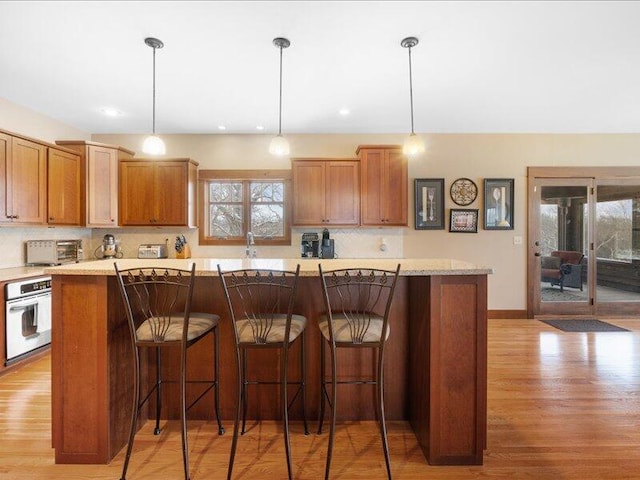 kitchen featuring wall oven, decorative light fixtures, a kitchen island, and a breakfast bar area