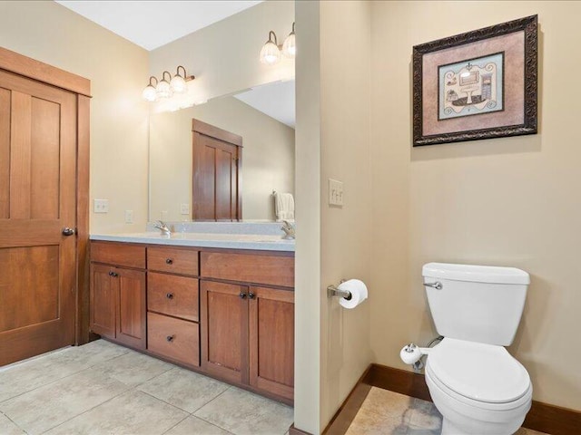 bathroom featuring double vanity, tile patterned flooring, toilet, and baseboards