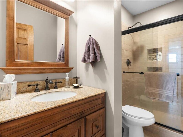 full bath with a stall shower, vanity, and toilet