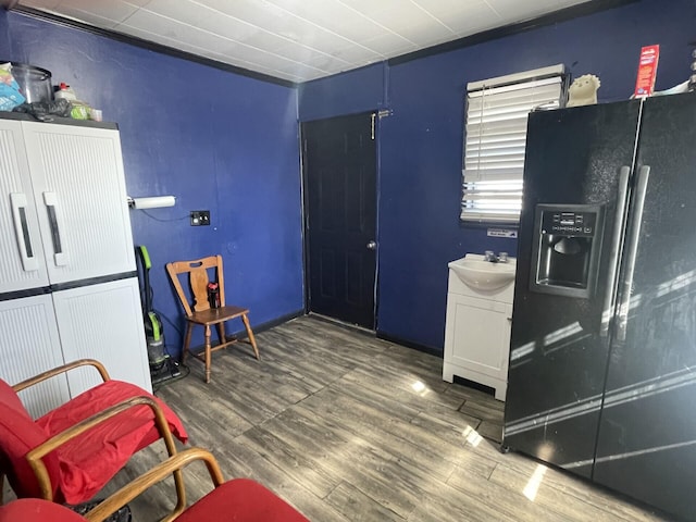 interior space featuring black refrigerator with ice dispenser, dark wood-type flooring, and a sink