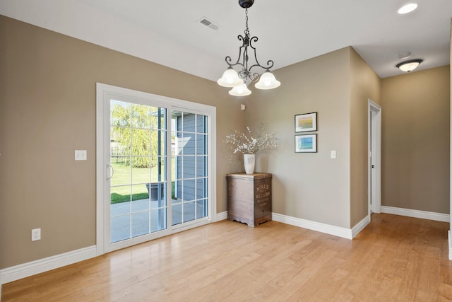 interior space featuring light wood-style flooring, visible vents, baseboards, and a notable chandelier