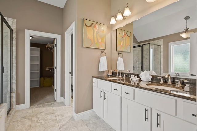 bathroom featuring a stall shower, a walk in closet, a sink, and double vanity