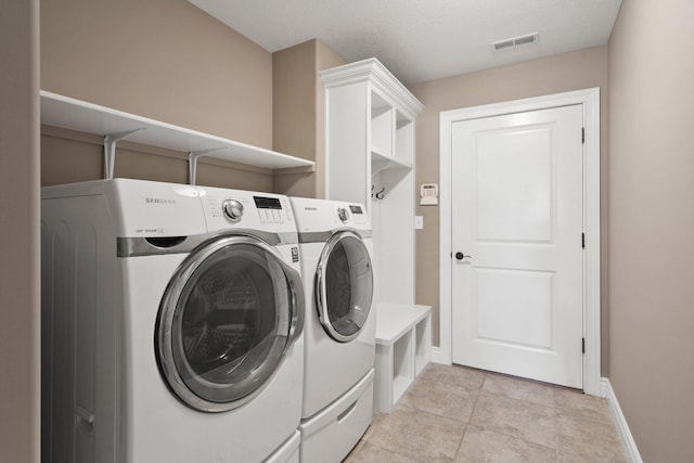 clothes washing area featuring a textured ceiling, washing machine and dryer, laundry area, visible vents, and baseboards