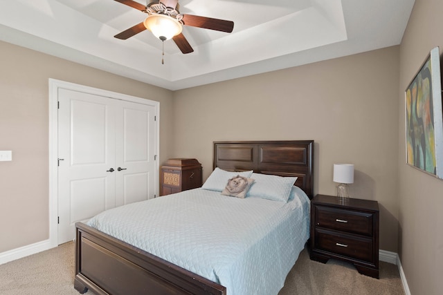 carpeted bedroom featuring baseboards, a tray ceiling, and ceiling fan