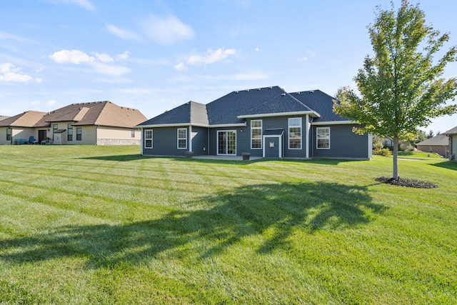 back of property with a patio area, a lawn, and roof with shingles