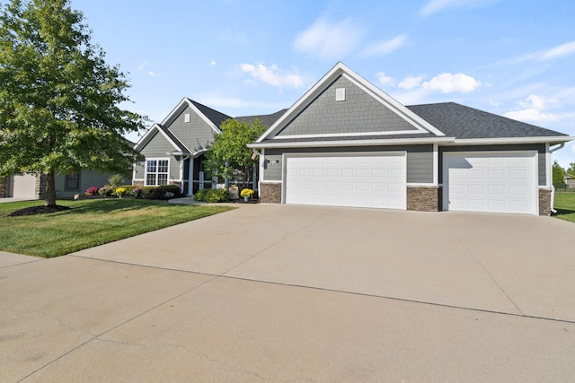 craftsman-style home with a garage, driveway, stone siding, and a front yard