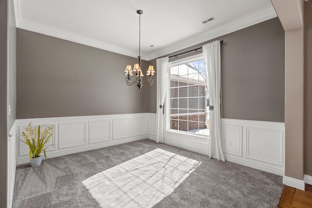 unfurnished dining area featuring a wainscoted wall, carpet, visible vents, and a notable chandelier