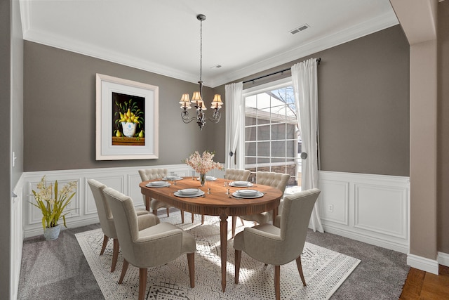 dining area featuring a wainscoted wall, ornamental molding, visible vents, and a notable chandelier