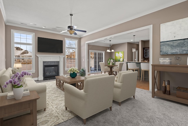 living area featuring crown molding, a fireplace with flush hearth, light carpet, baseboards, and ceiling fan with notable chandelier