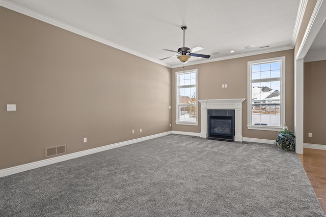 unfurnished living room with baseboards, visible vents, a tile fireplace, ceiling fan, and ornamental molding