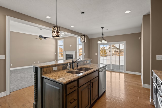 kitchen with a healthy amount of sunlight, dishwasher, a fireplace, and a sink