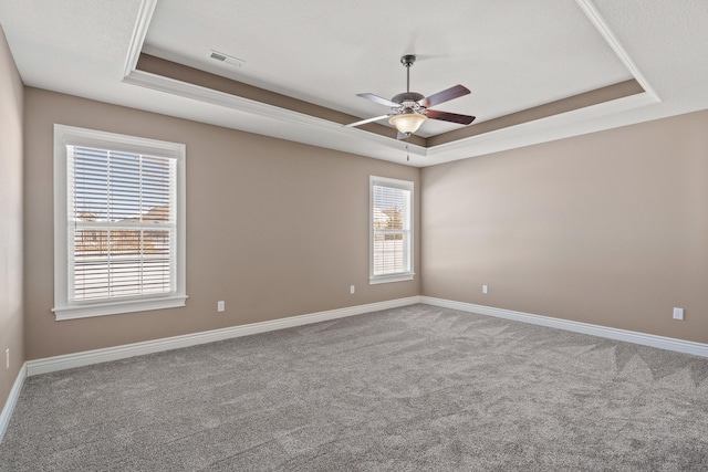 spare room featuring carpet, baseboards, visible vents, and a raised ceiling