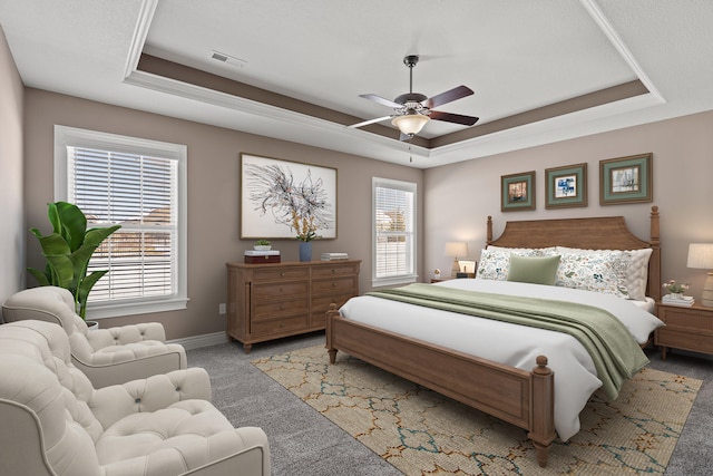 bedroom with light carpet, visible vents, multiple windows, and a tray ceiling