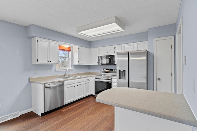 kitchen featuring appliances with stainless steel finishes, dark wood-style flooring, a sink, and visible vents