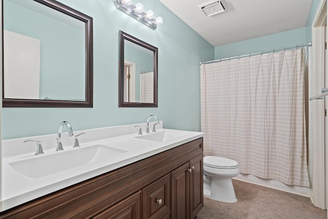 bathroom featuring visible vents, double vanity, a sink, and toilet