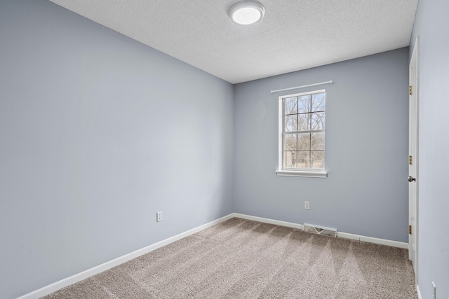 carpeted spare room featuring a textured ceiling, visible vents, and baseboards