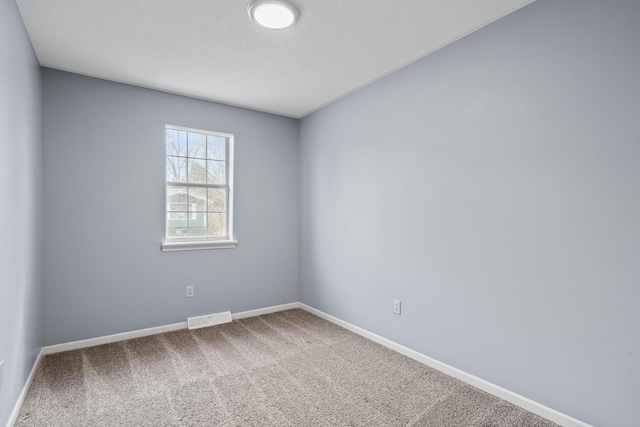 carpeted spare room featuring visible vents, a textured ceiling, and baseboards