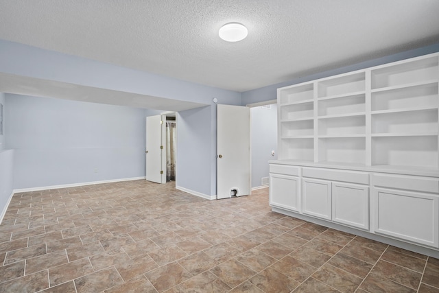 empty room with a textured ceiling and baseboards